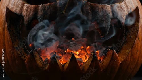 Cinematic 4K Seamless Loop Scary Carved Jack-o'-lantern with Burning Glowing Coals and Eerie Smoke in Dark Room