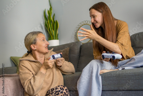 Fotografie Mother and daughter react emotionally to each other during competitive video game session at home