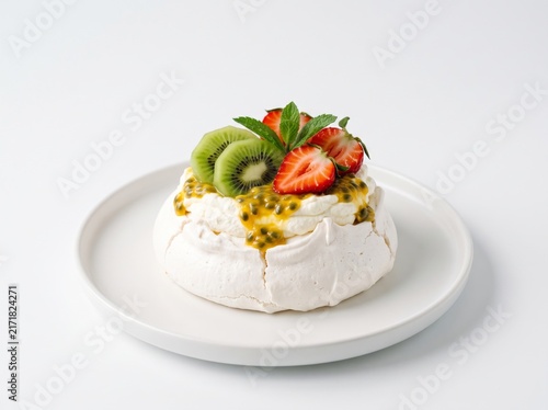 Mini pavlova meringue cake topped with passion fruit, kiwi, and strawberry on a white plate