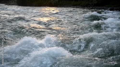 Close-up view of intense river rapids with sunlight glinting off the water, showcasing natural textures and dynamic motion.