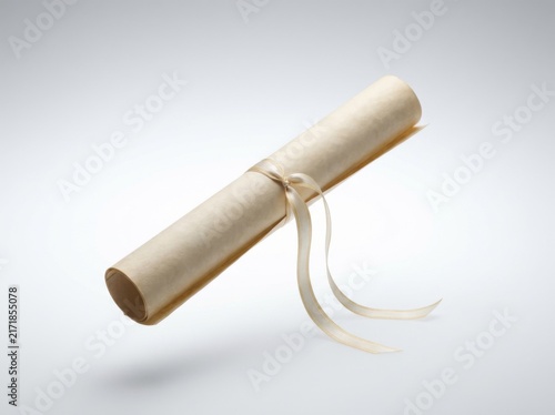 A neatly rolled aged parchment document is suspended against a bright white backdrop secured by a fine satin ribbon conveying concepts of academic success and historical significance.