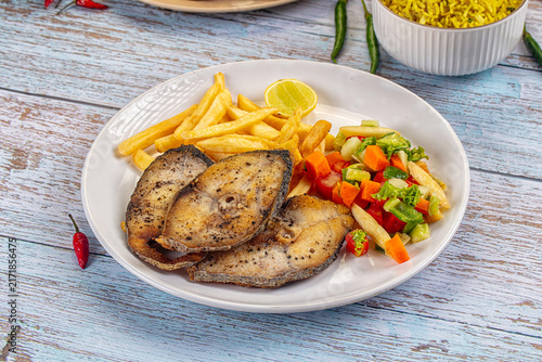 Canvas Print Grilled fish steak with fries and fresh salad on rustic table