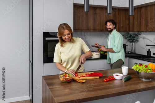 Bild auf Leinwand Couple cooking together in modern kitchen preparing fresh salad and vegetables