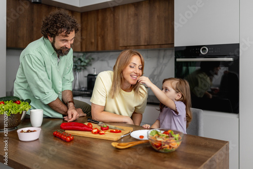 Foto Family cooking together in modern kitchen with parents and young daughter prepar