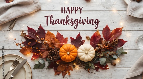 Happy thanksgiving greeting message on white wooden background with pumpkins and autumn leaves