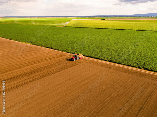 фотографія Tractor tilling and planting carrot seeds in freshly prepared soil alongside a v