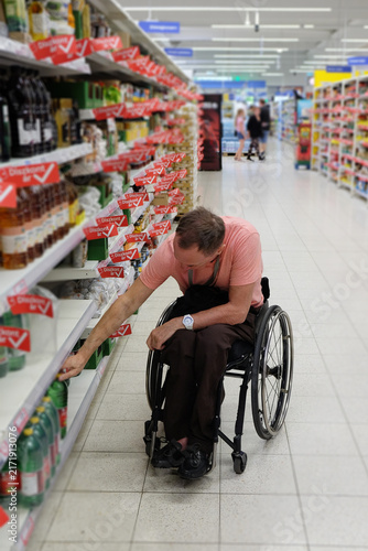 A man in a wheelchair chooses groceries in a supermarket