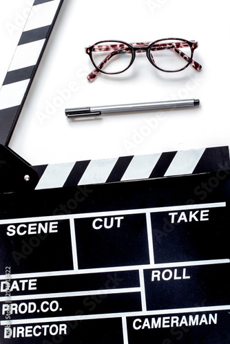 Screenwriter desktop with movie clapper board white background top view