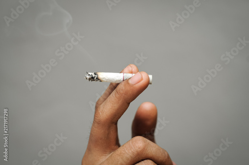 Konstfotografi a close-up view of a human hand holding a lit, burning cigarette between its fin