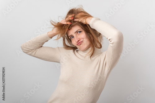 Quadro su tela Young redhead woman with tousled hair pulling at her temples and pouting, showin