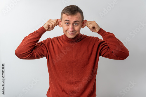 Canvastavla Young man stretching his ears outward with both hands, making a silly grimace an