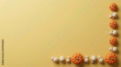 Halloween pumpkins and skulls arranged along a border on a pale yellow background