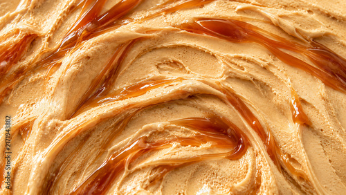 Extreme close-up of creamy peanut butter with glossy caramel swirls creating a rich and appetizing abstract food texture