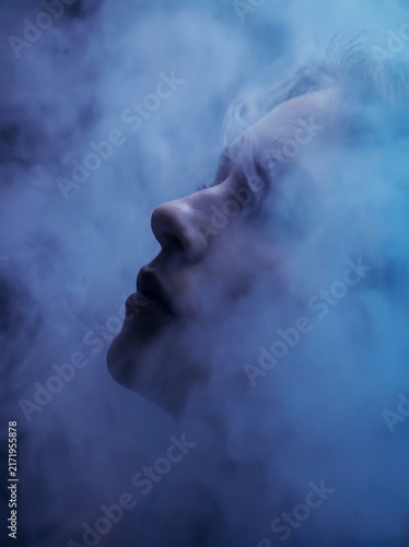 Ethereal profile of a human face obscured by swirling blue mist.
