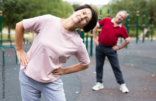 Canvastavla elderly man and woman do gymnastics on an outdoor sports ground
