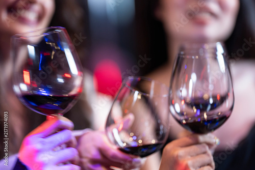 Foto A close-up of several glasses of red wine being clinked together in a celebratory toast cross in a tight cluster of dark red wine above the counter of a modern night bar