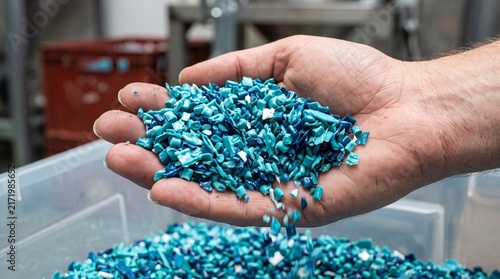 Recycled Plastic Pellets: A close-up shot showcases a hand holding a pile of vibrant blue recycled plastic pellets, hinting at the circular economy and sustainable manufacturing processes.