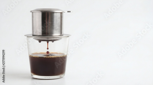 Vietnamese coffee dripping from metal filter into glass cup