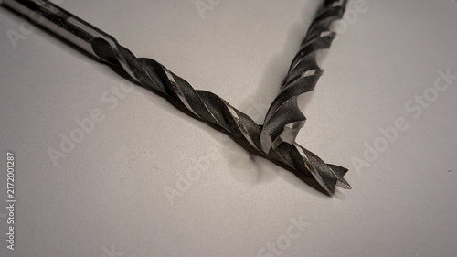Konstfotografi Two wood brad point drill bits arranged in a V-shape on a plain white surface