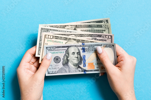 Foto Top view of different dollar banknotes in female hands on colorful background