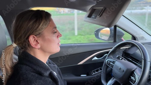 Woman driving car on road trip, side profile shot. Static interior camera angle captures her thoughtful expression during a peaceful afternoon journey.