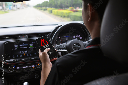 Driver holding a smartphone while driving, illustrating distracted driving and road safety awareness