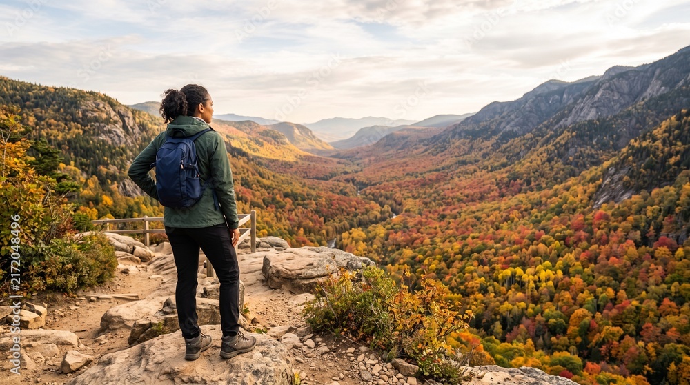 Obraz premium Female hiker admiring autumn valley view from mountain overlook during fall season travel adventure