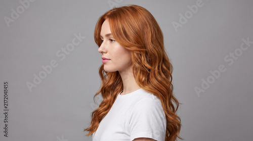 Side Profile of Young Woman with Long Wavy Copper Red Hair Isolated on Grey
