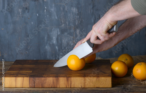 Chef Slicing Fresh Oranges on Wooden Board