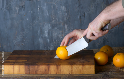 Chef Slicing Fresh Oranges on Wooden Board