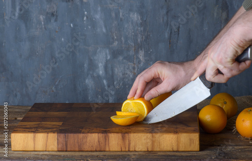 Chef Slicing Fresh Oranges on Wooden Board