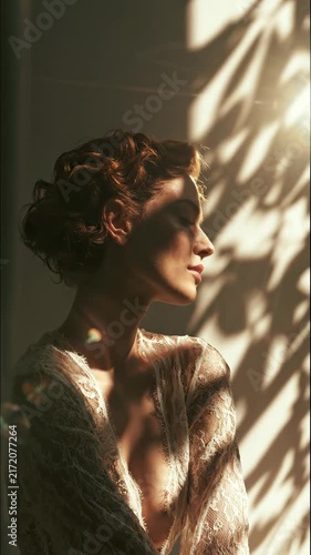 Elegant woman bathed in dramatic sunlight and shadow, with lace garment