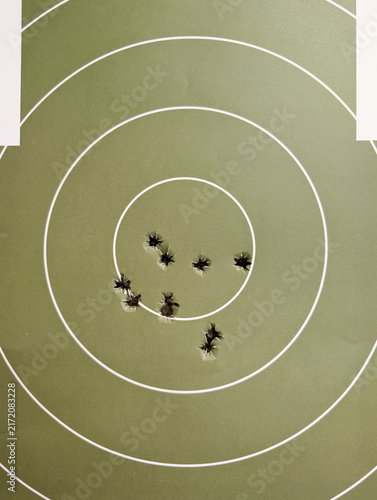 Принти на полотні Close-up view of 9mm bullet holes clustered on a green paper target bullseye aft