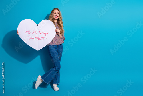 Obraz na płótnie Valentine mood young woman holds large heart sign against blue background