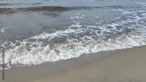 Gentle ocean waves washing onto a smooth sandy shoreline