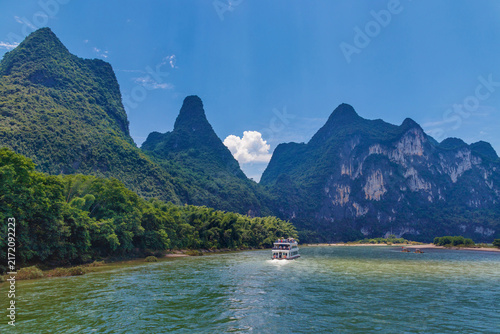 Foto Guilin, China, a passenger boat cruises the emerald Li River beneath dramatic ka