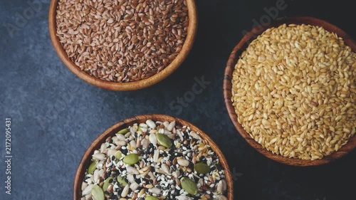 Three wooden bowls filled with mixed seeds and grains on a dark background