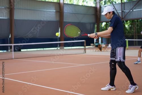 Cuadro en lienzo Focused young Asian male tennis player executing a backhand stroke on an indoor