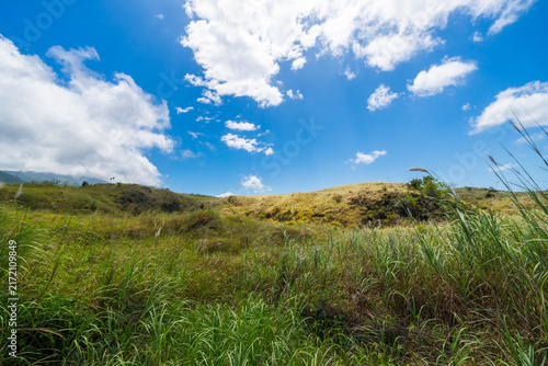 Serene rural landscape featuring lush green grass and rolling hills beneath a clear blue sky. A peaceful nature scene at the Batu Angus tourist area in Bitung, Indonesia.