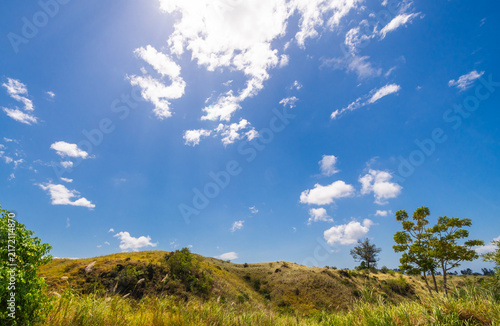Serene rural landscape featuring lush green grass and rolling hills beneath a clear blue sky. A peaceful nature scene at the Batu Angus tourist area in Bitung, Indonesia.