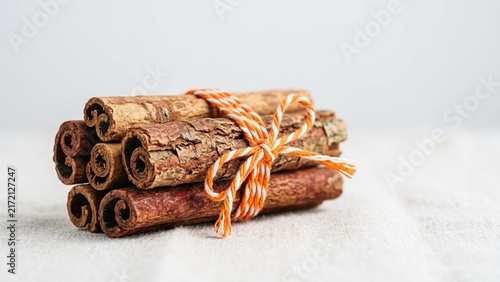 Stack of fresh cinnamon sticks tied with decorative orange and white twine
