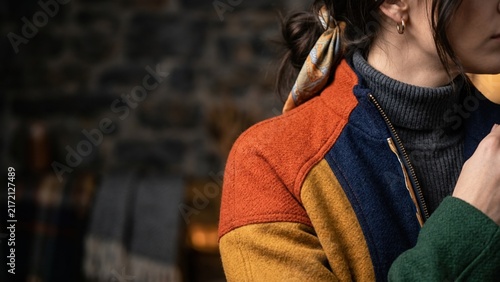 Stylish woman wearing a colorful wool patchwork jacket in a cozy rustic interior
