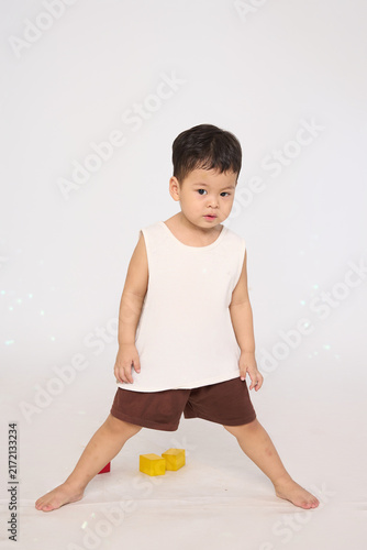 A 3-year-old toddler standing in a basic pose, wearing brown shorts and a white short-sleeved shirt.