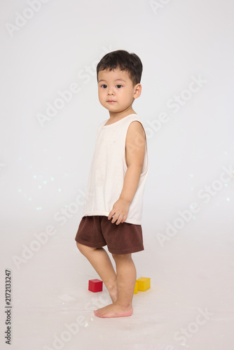 A 3-year-old toddler standing in a basic pose, wearing brown shorts and a white short-sleeved shirt.