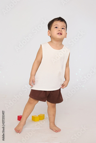 A 3-year-old toddler standing in a basic pose, wearing brown shorts and a white short-sleeved shirt.