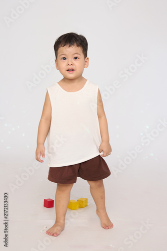A 3-year-old toddler standing in a basic pose, wearing brown shorts and a white short-sleeved shirt.