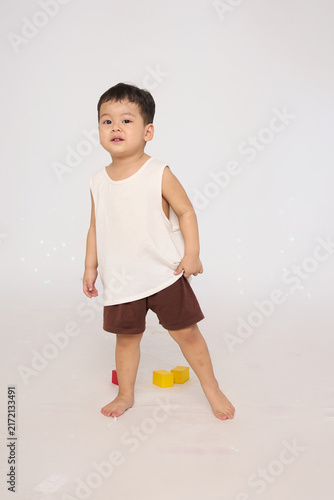 A 3-year-old toddler standing in a basic pose, wearing brown shorts and a white short-sleeved shirt.