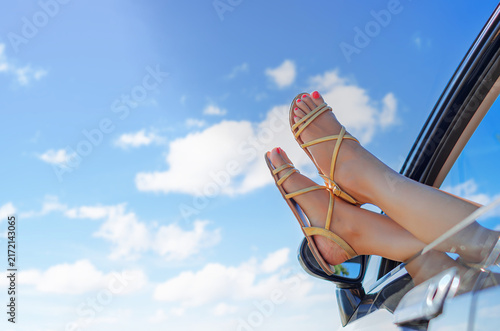 Fotografía A woman resting her feet in sandals out of an open car window against a clear blue sky