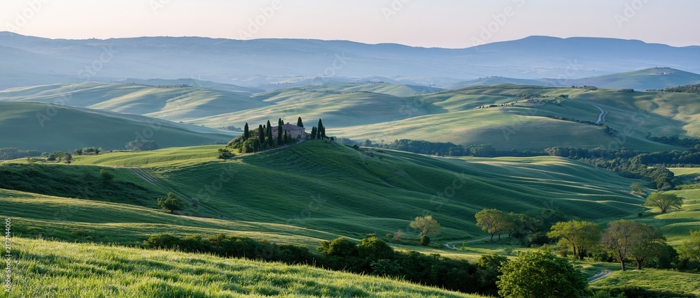 Naklejka premium The Serene Rolling Hills Landscape with Verdant Valleys and Distant Mountains