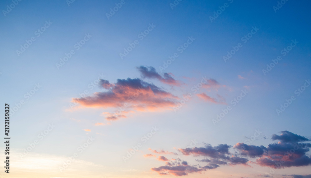 Obraz premium Beautiful sunset sky with soft clouds and vivid blue to orange gradient background.Panoramic sky background during golden hour sunrise with colorful clouds and copy space.